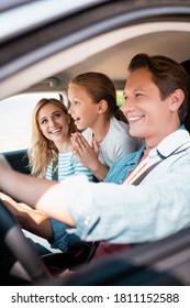 Selective Focus Of Surprised Kid Looking Away While Sitting Near Parents In Car During Weekend