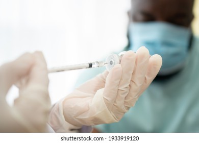 Selective focus of syringe, African American Wear a medical mask and being covid vaccinated for the prevention of coronavirus and flu. Concept of immunization from inoculation - Powered by Shutterstock