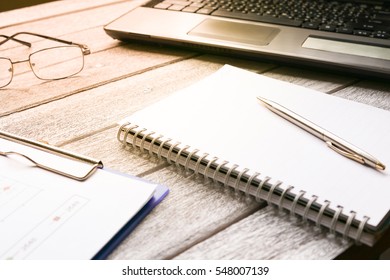 Selective focus table : eyeglass , mobile phone, laptop, note book and pen on the wooden table.working Business concept with effect light added