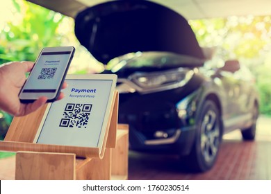 Selective focus to tablet with blurry smart phone and car service. Blurry hand holding smartphone and scanning qr code to payment on car service center background. QR payment.