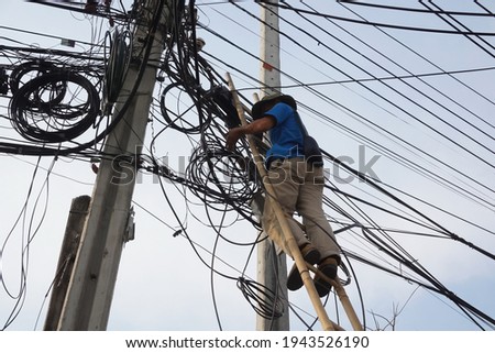 Selective focus technician man stands on ladder without safety belt is risk work while fixing fiber optical cable. Unsafe workplace, risk work, unsafe acts concept.                                