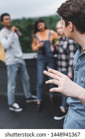 Selective Focus Of Teenager Smoking Cigarette With Friends On Roof 