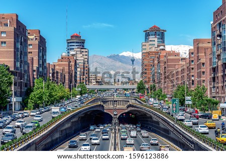Selective focus. Tehran,Iran,Famous view of Tehran, Flow of traffic around Tohid Tunnel with Milad Tower and Alborz Mountains in Background, Tunnel one of longest urban tunnel in Middle 