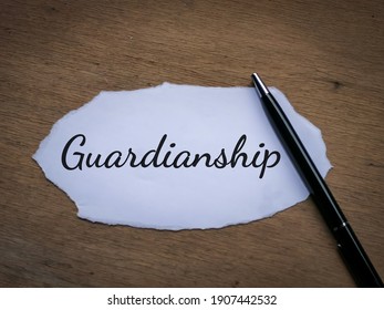 Selective focus top view text Guardianship written on a piece of paper with a pen. 