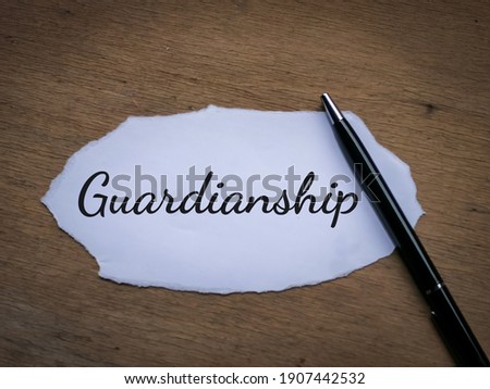 Selective focus top view text Guardianship written on a piece of paper with a pen. 