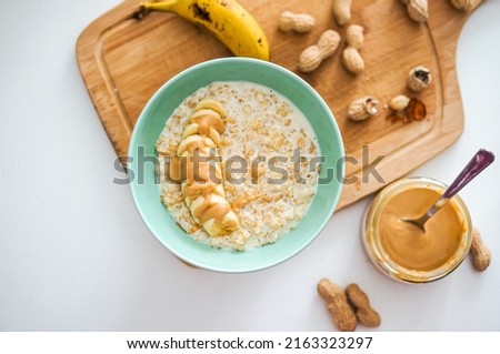 Selective focus top view of tuquoise color bowl of oatmeal porridge with banana, groundnut and peanut butter