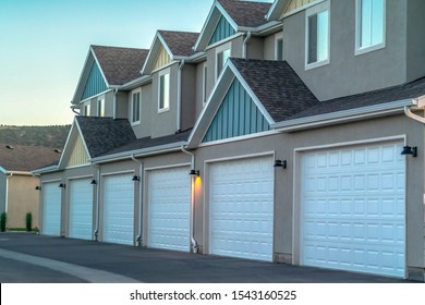 Selective focus of townhomes with white garage doors against mountain and sky