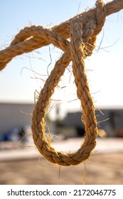 Selective Focus Of Twisted Rope Knotted From Plant Fibers In Backlight. Concept Of Bonding, Hanging, Execution.