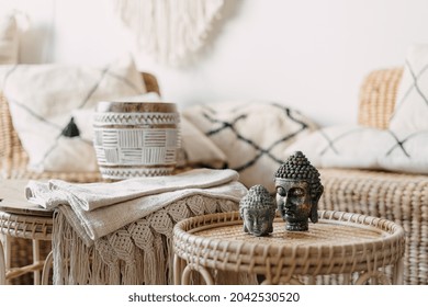 Selective focus at two Buddha statue standing on bamboo coffee table in bright living room interior at bohemian style. Concept mental health and recreation. House with natural materials furniture