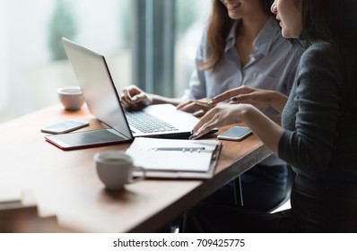 In Selective Focus Of Two Confident Young Business People Looking At Laptop Monitor While Their Colleagues Working In The Background. Setup Studio Shooting.