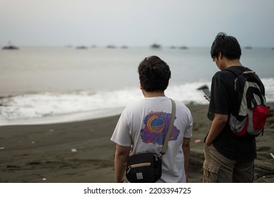 selective focus of two men looking at the ocean in the afternoon. two men with their backs to the camera