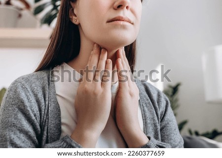 Selective focus of unhealthy sad young caucasian woman hold hands over sore throat feeling discomfort. Painful neck and frowning, thyroid disorders, suffering sore throat, tonsils inflammation concept