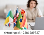 selective focus of various international flags near blurred laptop and language teacher having online lesson at home