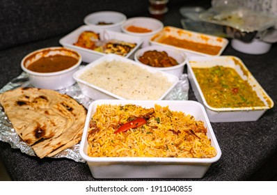 Selective Focus Of Vegetable Biryani In A White Takeout Box. Many Foods In Takeout Boxes Blurred In The Background.