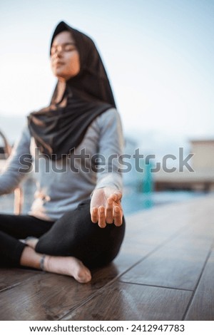 selective focus veiled girl in meditation pose near swimming pool in the morning