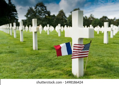 Selective focus view of view of cross headstones in the American Cemetery at Omaha Beach in Normandy with French and US flags