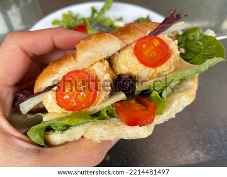 Selective focus view of hand holding a cute Halloween Monster Burgers or sandwiches, egg mayo, on white ceramic plate. Halloween food concept, celebration party, Vegan Food. Kid party food