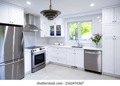 Selective focus view of large modern kitchen with white cabinets, counter and backsplash, as well as stainless steel appliances