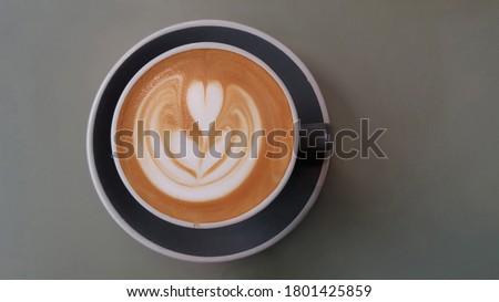 Selective focus view on the latte art at the top of the cup of hot Caffe latte on wooden picnic table. It is a coffee drink made with espresso and steamed milk.