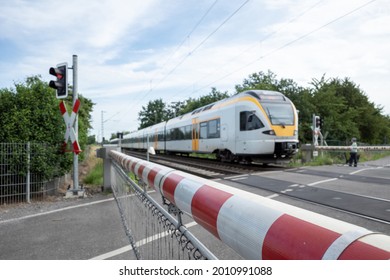 Selective focus view at red and white level crossing railway barrier which block the road and regional train move on the rail on countryside in Germany.	 - Powered by Shutterstock