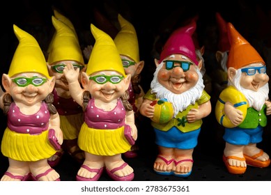 Selective focus view of rows of cute funny decorative male and female garden gnomes in summer clothes and sunglasses 