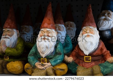 Selective focus view of rows of cute decorative garden gnomes in yoga or meditation poses 