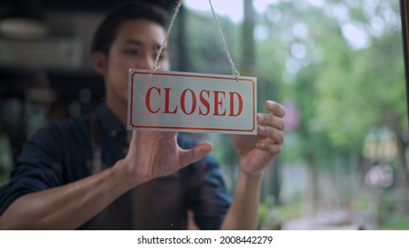 Selective focus, View through window, Close up Handsome young man owner hanging storefront sign to close at cafe or restaurant, small business service concept - Shutterstock ID 2008442279