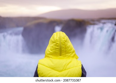 SELECTIVE FOCUS Wanderlust Non Gender Person Staring At Huge Waterfall In Iceland Waring A Fashion Yellow Jacket