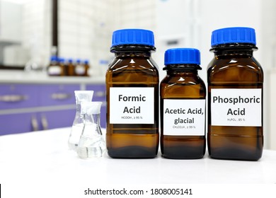 Selective focus of weak Formic, Acetic and Phosphoric acids in brown amber bottle. Blur white laboratory backdrop with copy space.
