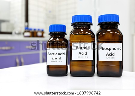 Selective focus of weak Formic, Acetic and Phosphoric acids in brown amber bottle. Blur white laboratory backdrop with copy space.