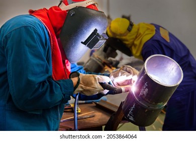Selective focus to welding area.  Two welder are assembling the workpiece by Tungsten Inert Gas Welding process (TIG). The workers are testing a welding in the workshop.