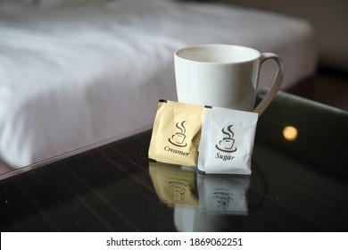 Selective focus of white cup with sugar and creamer on the table in hotel room