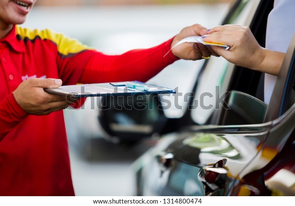 Selective focus to woman driver pay credit card\
with staff for fuel in gas\
station.