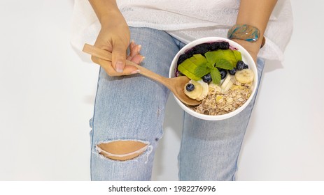 Selective Focus Of Woman Hand Eating Diet Program With Yogurt Blueberry ,avocado,banana,as Granola Parfait In A Bowl With Spoon On White Background-Healthy Food Concept