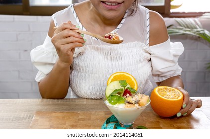 Selective Focus Of Woman Hand Eating A Healthy Yogurt Strawberry ,avocado,banana,as Granola Parfait In A Bowl -Healthy Eating And Diet Plan Concept  In Her Home