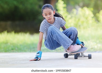 Selective Focus, Young Asian Girl Wearing Protective Gear At Her Hands Surfing Or Skating On The Rink In The Morning. Play Sports Safely Concept.