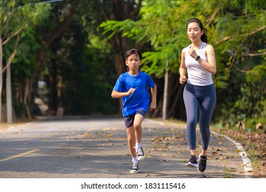 Selective focus at young Asian woman and boy running with happy in a park during summer day in a morning. - Shutterstock ID 1831115416