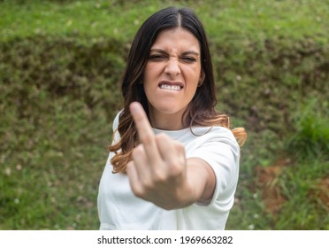Selective focus of a Young latina woman wearing casual clothes showing middle finger doing you bad expression, provocation and rude attitude. Fresh Air