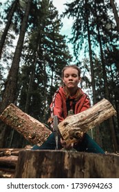 Selective Focus. Young Strong Girl Teenager Chopping Wood With Axe Blow In Forest. Purposeful Ambitious Teen With Male Character. Camping And Wild Travel. Lumberjack Woman Cuts Firewood For Bonfire