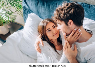 Selective focus of young woman touching boyfriend on bed at morning