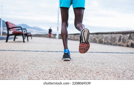 Selective Focus.Black Male Athlete Dressed In Sportswear, Running On Promenade By The Sea.