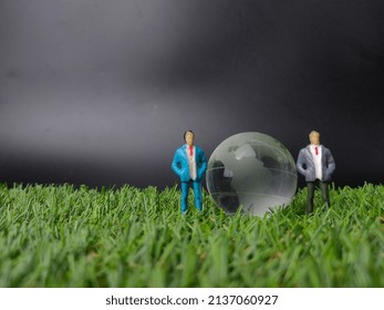 Selective focus.Crystal earth globe with miniature people on a grass background with copy space.
