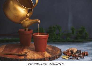 Selective Focused, Herbal tea is under process of Pouring in Earthen cups known as Kulhad. Locally called Kulhad chai or cutting chai or masala chai or matka tea. Mud pot tea cups with bio degradable
