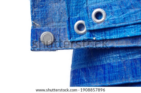 Selective focused photo of used blue tarpaulin with eyelets isolated on white background with space for runaround or wraparound text 