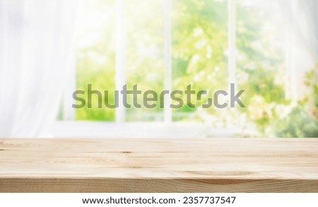 selective focus.Empty of wood table top on blur of curtain window and abstract green from garden with sunlight .For montage product display or design key visual layout