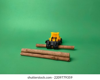 Selective Focus.Excavator With Wooden Stick On Green Background. Conceptual Image Of Illegal Logging.