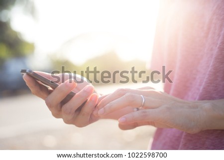 selective focus.hand women holding and using mobile phone at outdoor with copy space for text.concept for business,people communication,technology electronic device.