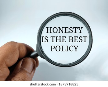 Selective focus.HONESTY IS THE BEST POLICY in black word with hand holding magnifying glass isolated on white backround.Business and finance concept.