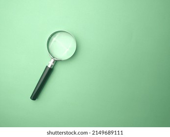 Selective Focus.Magnifying Glass On A Green Background With Copy And Text Space.