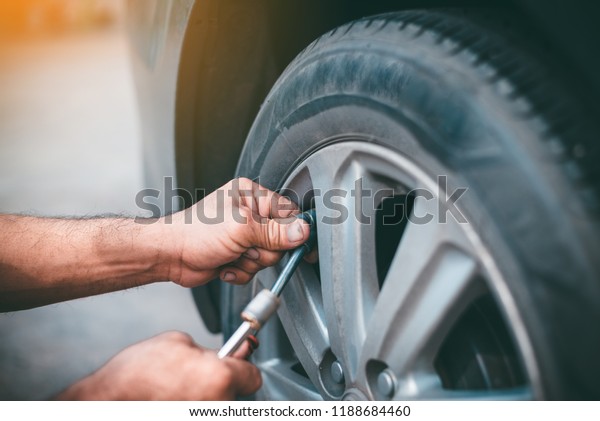 Selective focus,Old man checking air\
pressure and filling air in the tires of oldcar,copy\
space.